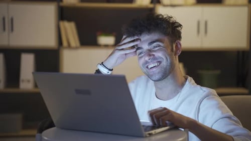 Smiling Young Man Using Laptop at Night