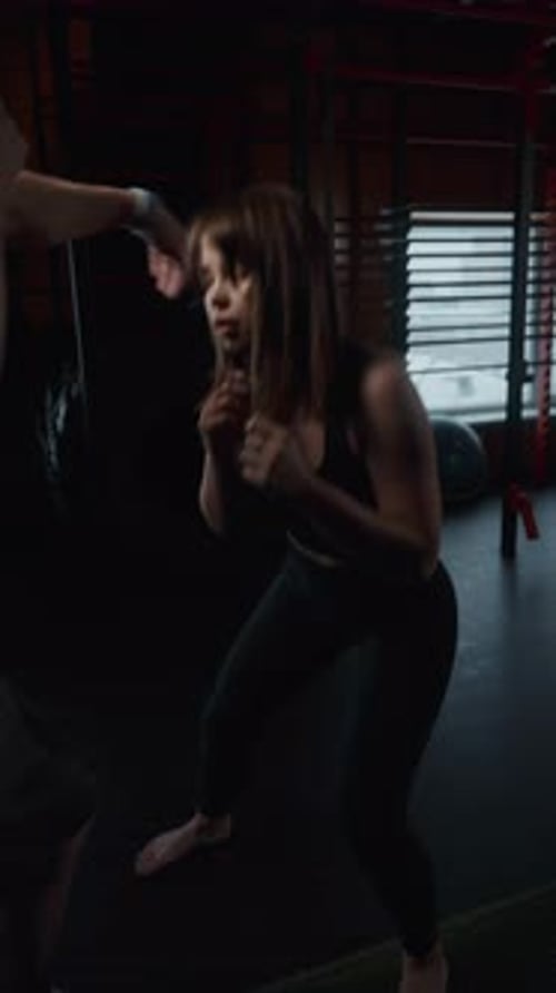 A Woman is Boxing in a Gym with a Man Watching Her
