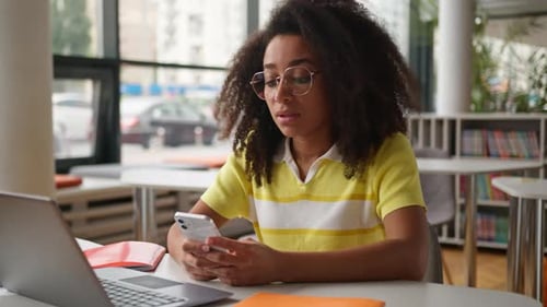 Girl Uses Smartphone in Bright School Library