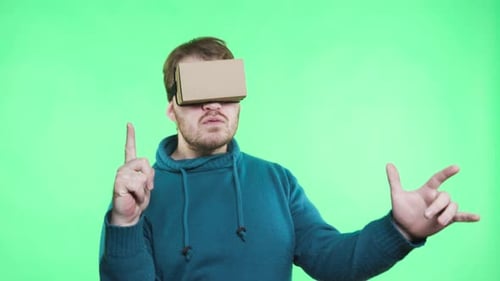 Man uses cardboard virtual reality headset on green screen