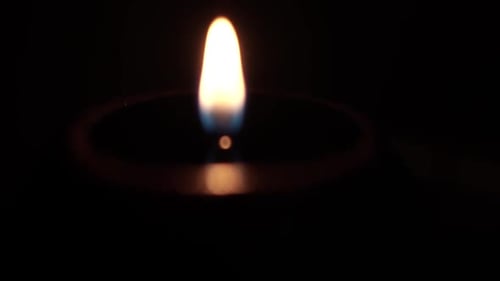 Glowing Candle Flame Flickering in the Darkness