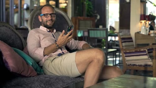 Portrait of Young, Happy Man with Smartphone Sitting in Trendy Cafe 30s