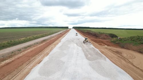Bulldozer and a Road Roller are Laying Rubble on a New Road Before Asphalting
