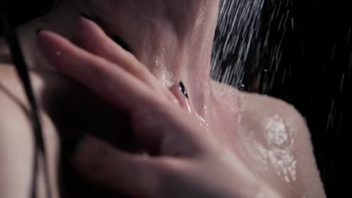 Sportlicher Frauenkörper im Badezimmer, berühren Sie sich mit Leidenschaft unter den Wassertropfen in Slowmo...