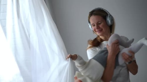 Mother and Baby Playing near Window with Curtains