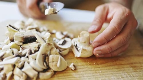 Man cutting mushrooms on a wooden cutting board