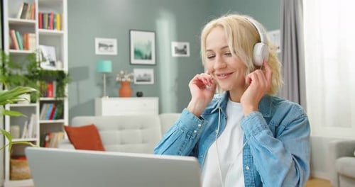 Close Up of Caucasian Joyful Young Pretty Female Putting on Headphones and Relaxing Listening to