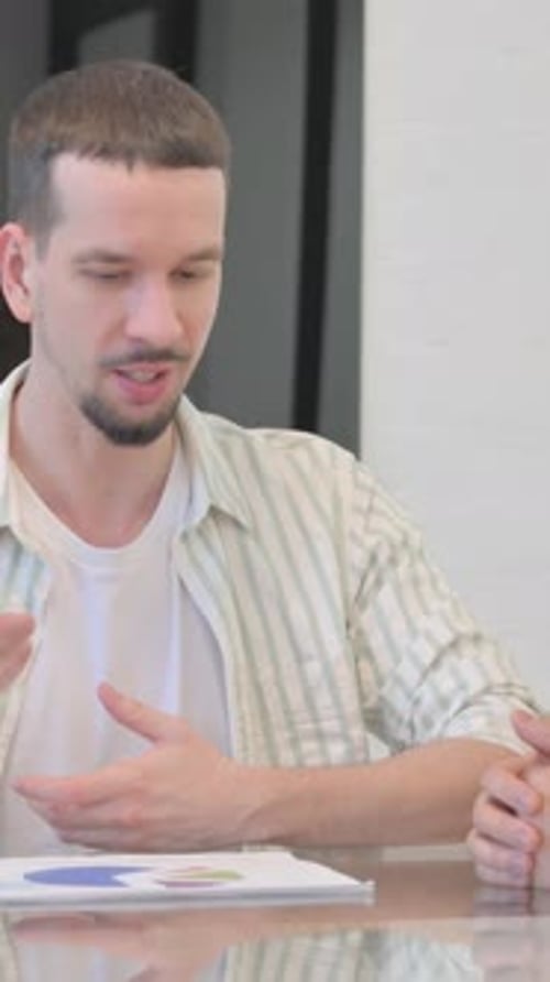 Man Explains Chart to Woman at Boardroom Table