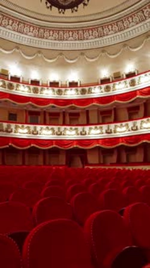 Empty seats in the auditorium of the opera house. Beautiful theatrical hall with rows of red chairs.