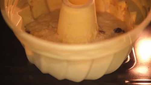 Cake batter rising in a bundt pan inside an oven. Close-up photography of baking process, timelapse.