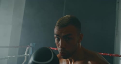 Cinematic slow motion shot of a professional young muscular shirtless man is practicing shadow box