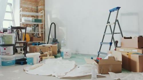 Interior of Room with Boxes, Paint Buckets and Ladder during Home Improvement