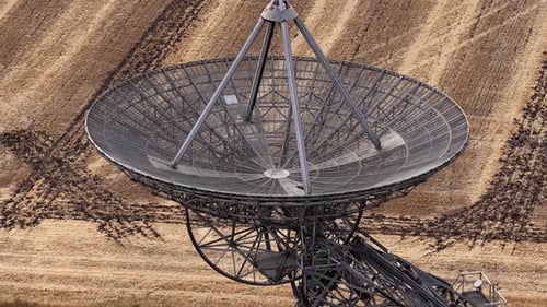 Aerial View of Large Satellite Dish Moving in Field
