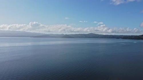 Aerial top view of peaceful calm dark blue sea water surface, cloudy sunset or sunrise sky and silho