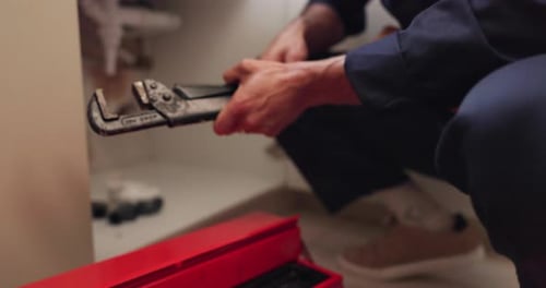 Man Plumbing Pipe Under Sink With Wrench