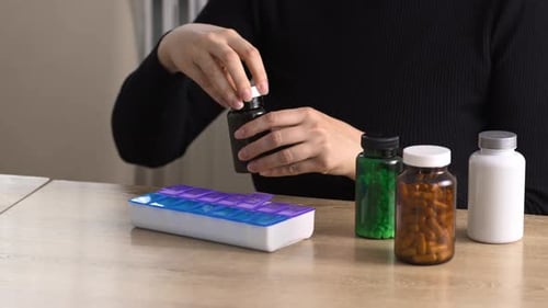 Woman Organising Pills with Pill Organizer on Table