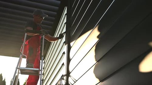 Man on Ladder Does Repairs on Building