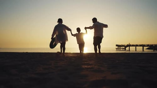 Kleiner Junge hält Hände an Mama und Papa Familie rennt zusammen zum Meer Silhouette von Menschen auf