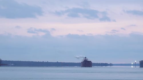 Static shot of freighter going up a calm river on a cloudy day