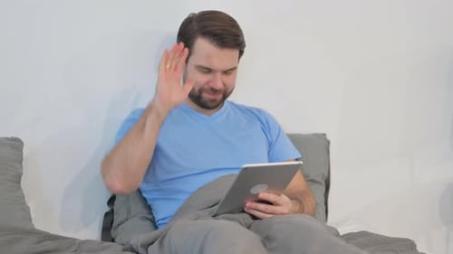 Man Using Tablet in Bed