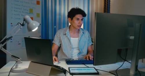 Asia male use computer remote working on desk in living room at home office overtime night.