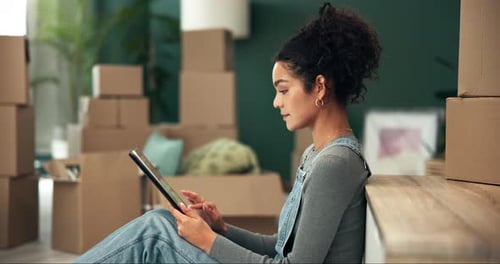 Woman Using Tablet Among Moving Boxes in Apartment