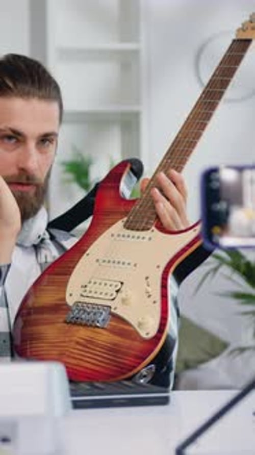 Un profesor bloguero caucásico graba un tutorial de clase en vídeo para tocar la guitarra eléctrica en música moderna