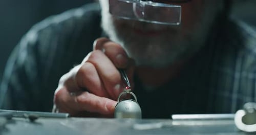 Slow motion of experienced goldsmith working on a handmade jewelry ring with precious diamond ston