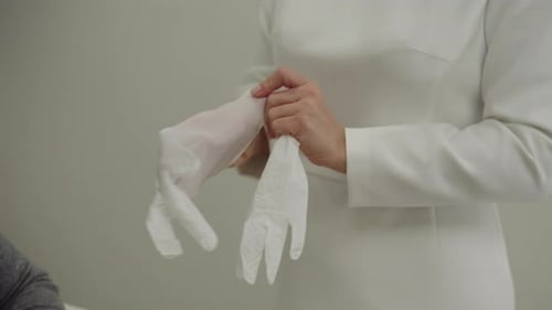 Professional Medical Worker Putting on White Sterile Latex Gloves in Preparation for Procedure