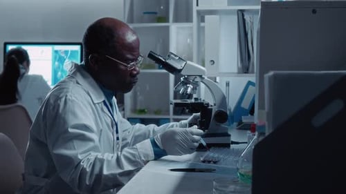 African American Biochemist Dropping Test Blood on Microscope Specimen Glass