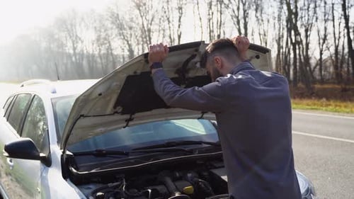 An Unfortunate Driver is in Shock Near a Broken Car in the Middle of the Highway