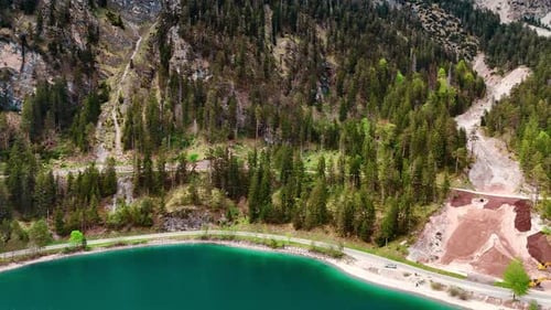 Drone footage approaching the waterscape of turquoise lake at the foot of the mountains.