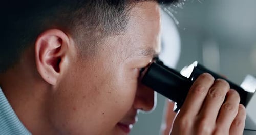 Young Adult Looks Through Microscope in Science Lab