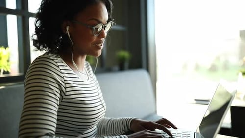 Smiling Woman Working on Laptop with Headphones Indoors
