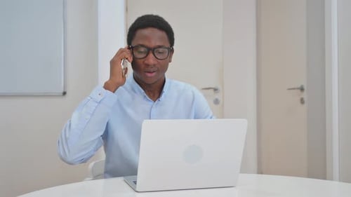 Man with Laptop Talking on Mobile Phone