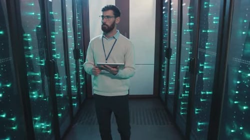 Technician with Tablet Inspecting Data Servers in Datacenter
