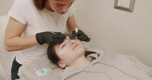 Extensão de cílios de esteticista para mulher jovem em um salão de beleza