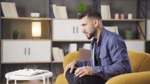 Worried Young Adult Meditating Indoors on Yellow Chair