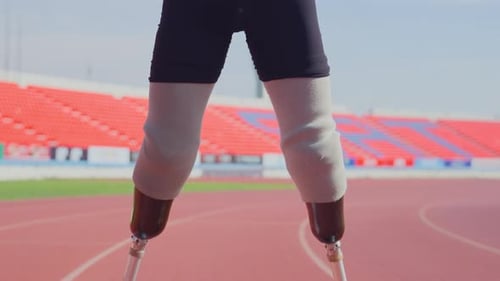 Close up sport man athlete with a prosthesis on his leg stand on racetrack of stadium to warm up