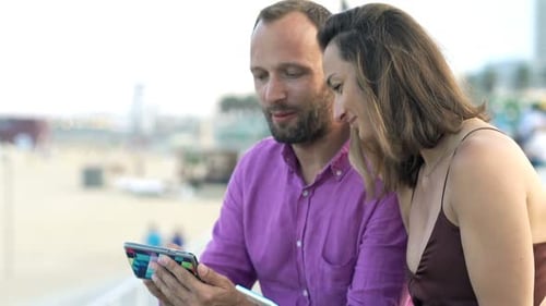 Young Couple Using Smartphone Sitting Near Beach in City Adult