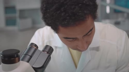 Young Adult Scientist Using Microscope in Lab