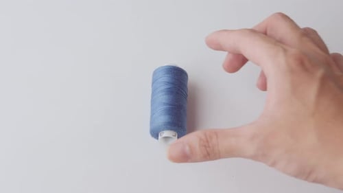 Blue thread on its spool held by a hand