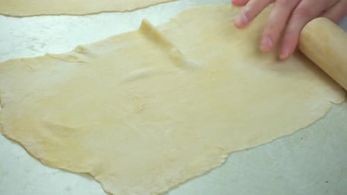 Close-Up of Woman's Hands Rolling Dough with a Wooden Rolling Pin