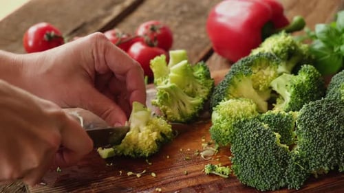 Hands Cutting Raw Broccoli with Knife While Cooking Healthy Vegan Meal