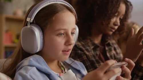 Girls Playing on Cell Phones with Headphones Indoors