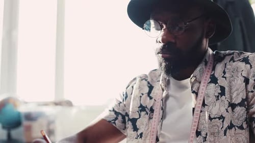 Close Up View of Serious Eccentric AfroAmerican Designer with Measuring Tape on His Neck Working