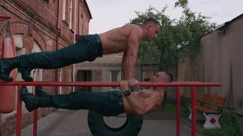 Muscular Men Performing Parallel Bar Workout in City