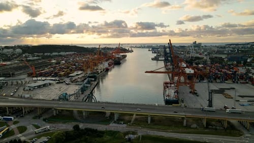 Aerial shot showing industrial harbor of Gdynia with cranes for freight and driving cars on bridge o