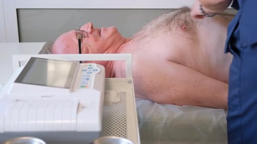 A Professional Doctor Makes a Cardiogram of the Heart for an Elderly Man Physical Examination