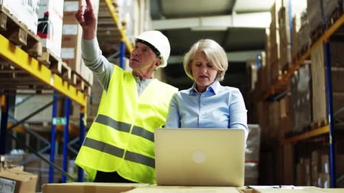 Senior Woman Manager with Laptop and Man Worker Working in a Warehouse